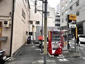 橋を渡ると駐車場（タイムズ）があるので左に曲がる（左に曲がり２つ目の細い道を右に曲がれば当ビル着）